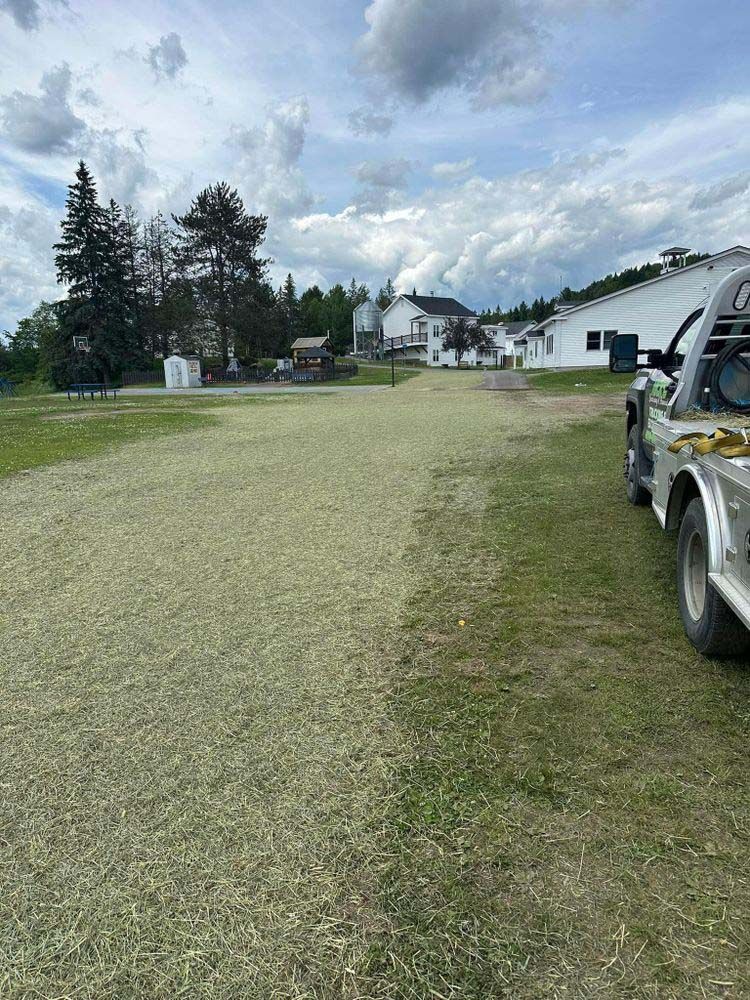 Two trucks are parked in a grassy field.