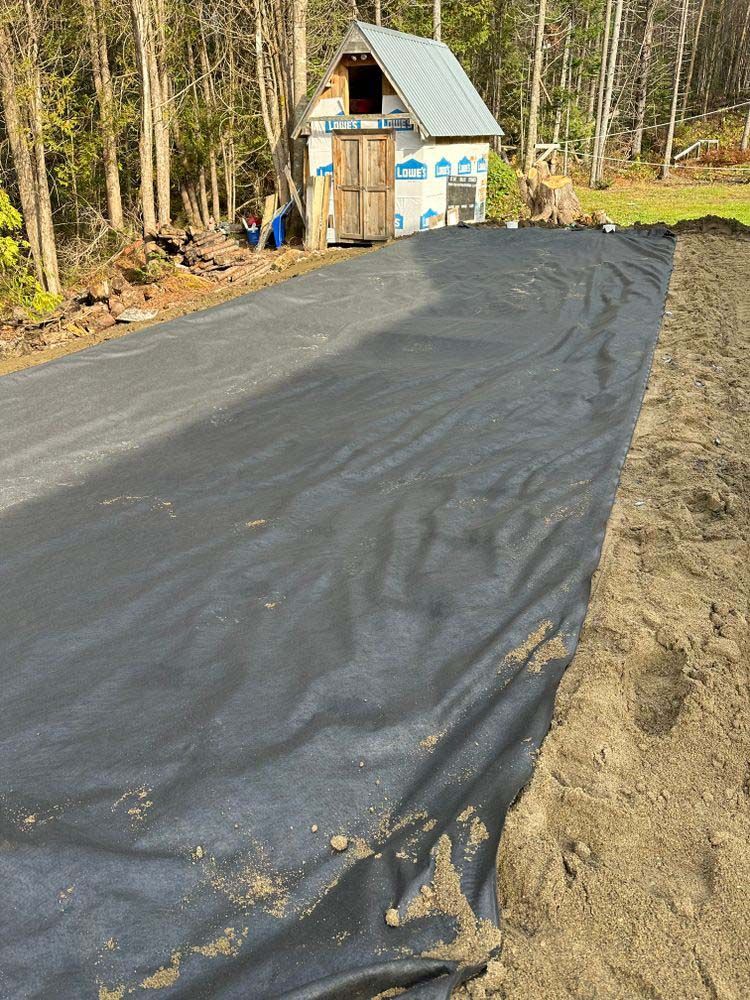 A small house is being built on the side of a dirt road.