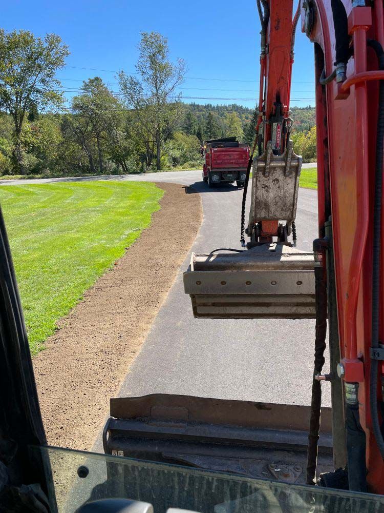 A red truck is driving down a road next to a red excavator.