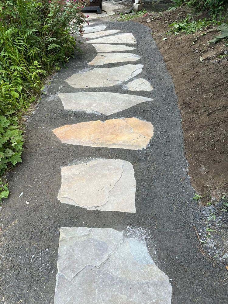 A stone walkway is being built on the side of a road.