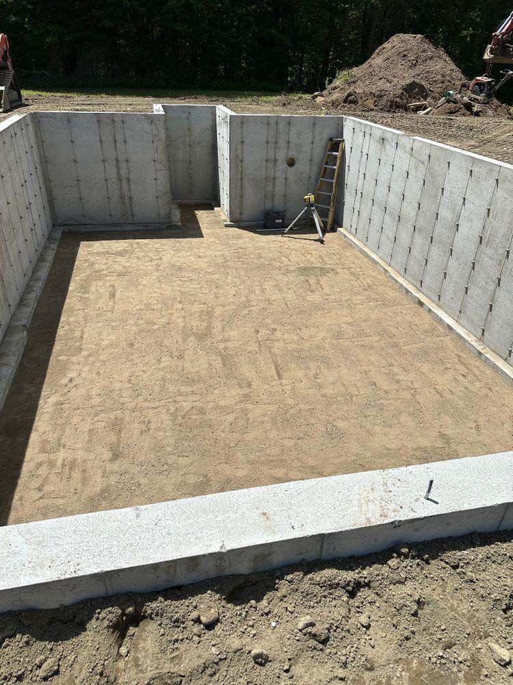 A concrete basement under construction with a pile of dirt in the middle.