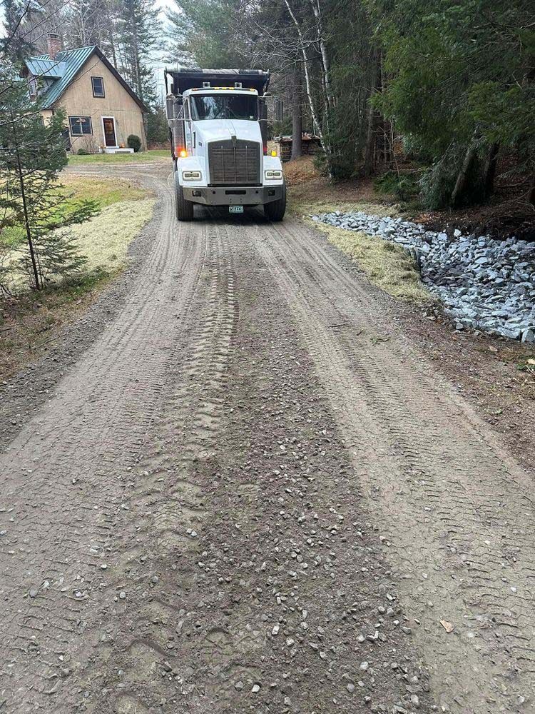 A dump truck is driving down a dirt road.