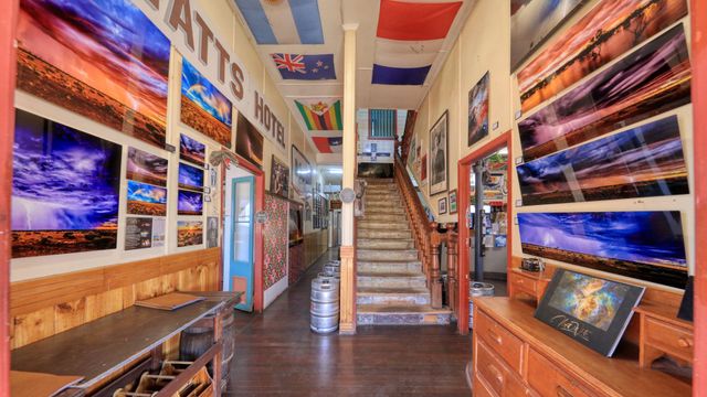 Bright hallway with framed photos, a central staircase, and colorful ceiling flags in a gallery-like interior