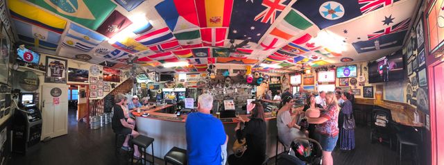Busy colorful bar packed with patrons under flags and neon signs
