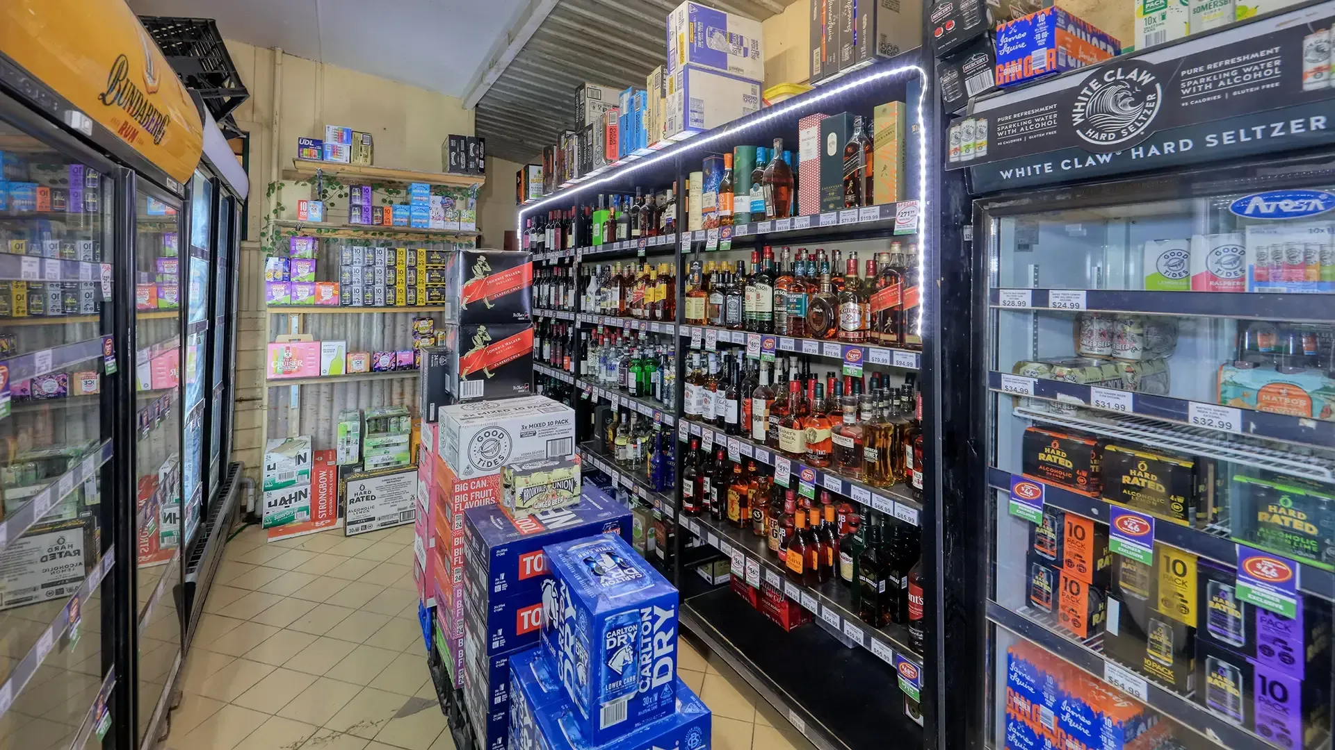 Convenience store aisle with refrigerators, snacks, and drinks on shelves