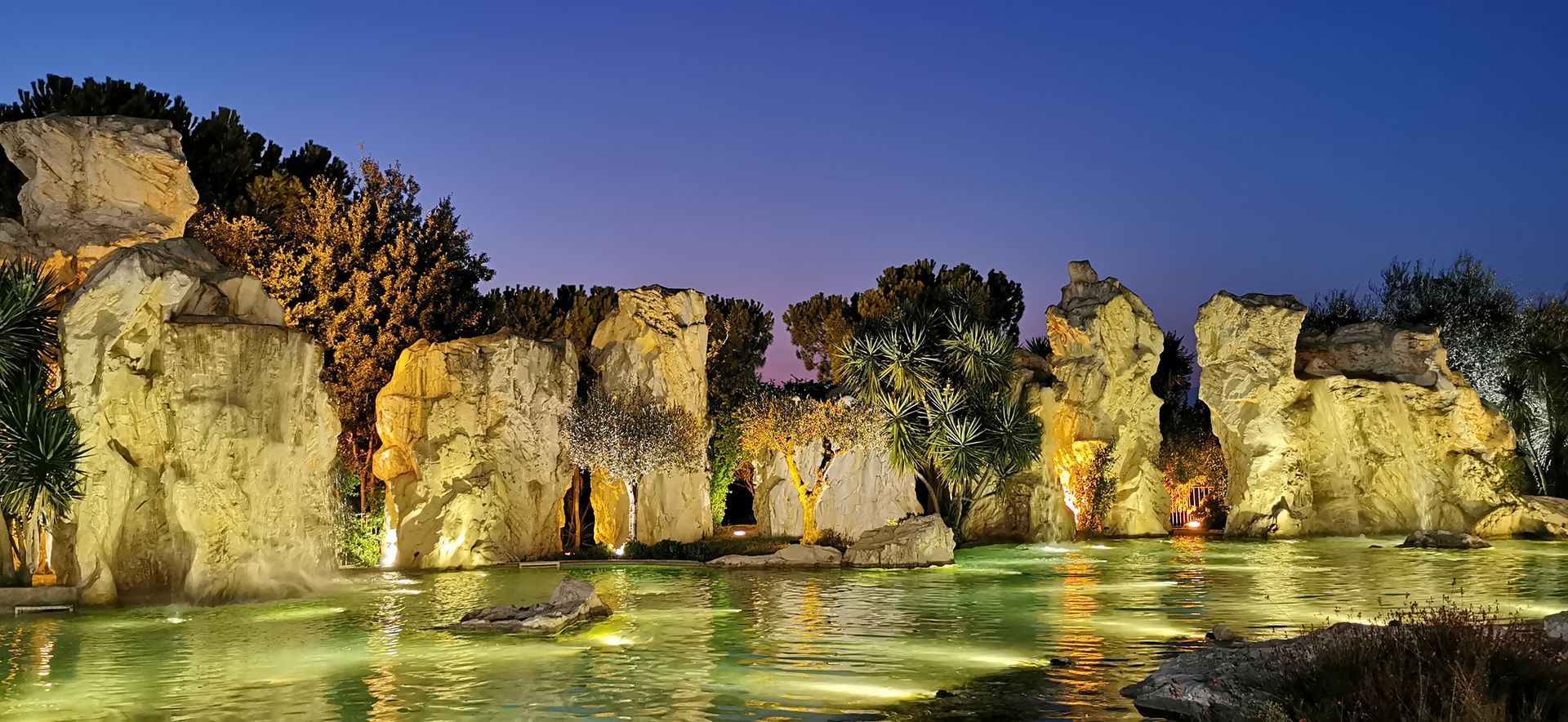 Un grande specchio d'acqua circondato da rocce e alberi di notte.