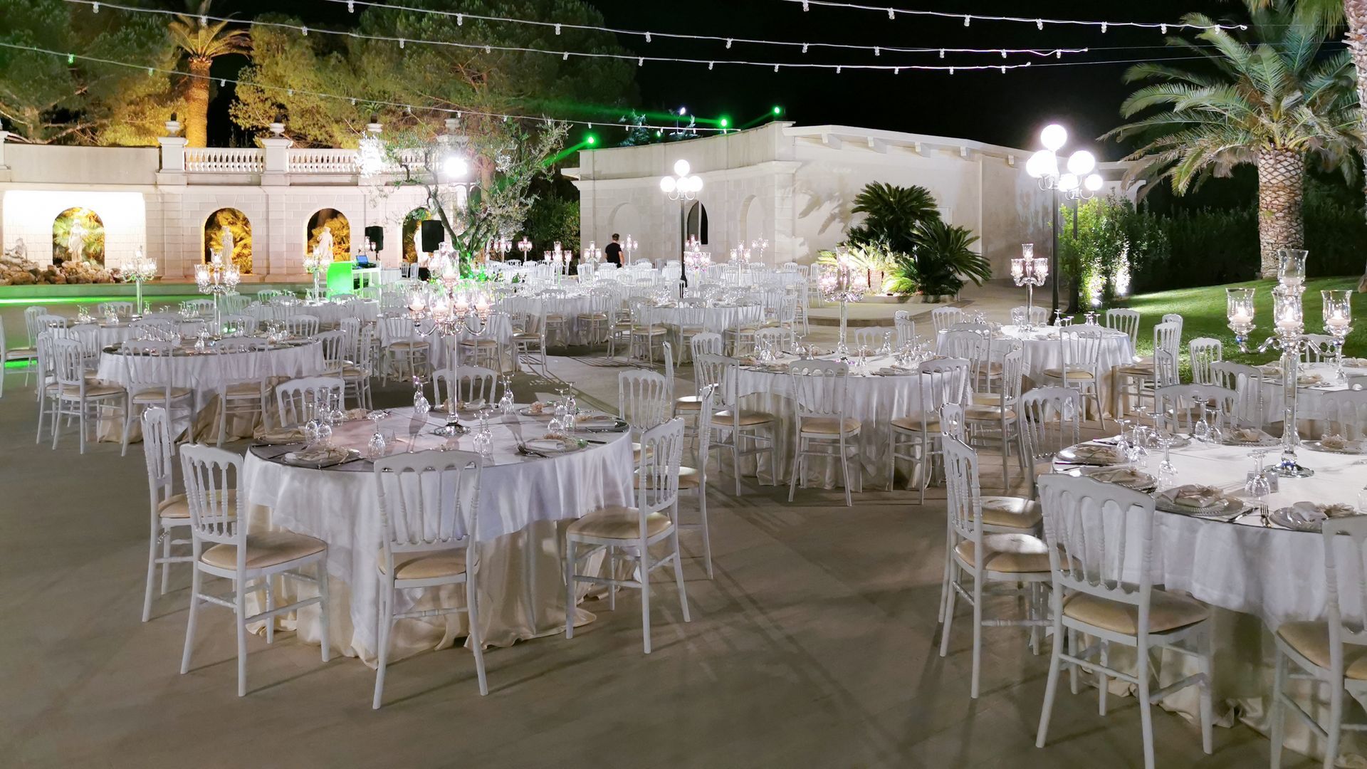 Una grande sala con tavolo e sedie allestita per un ricevimento di nozze.