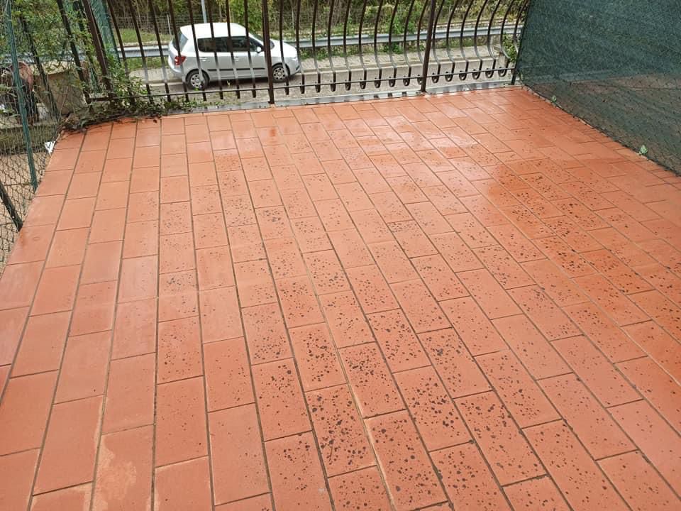Un balcone pulito con tegole rosse e un'auto parcheggiata sullo sfondo.