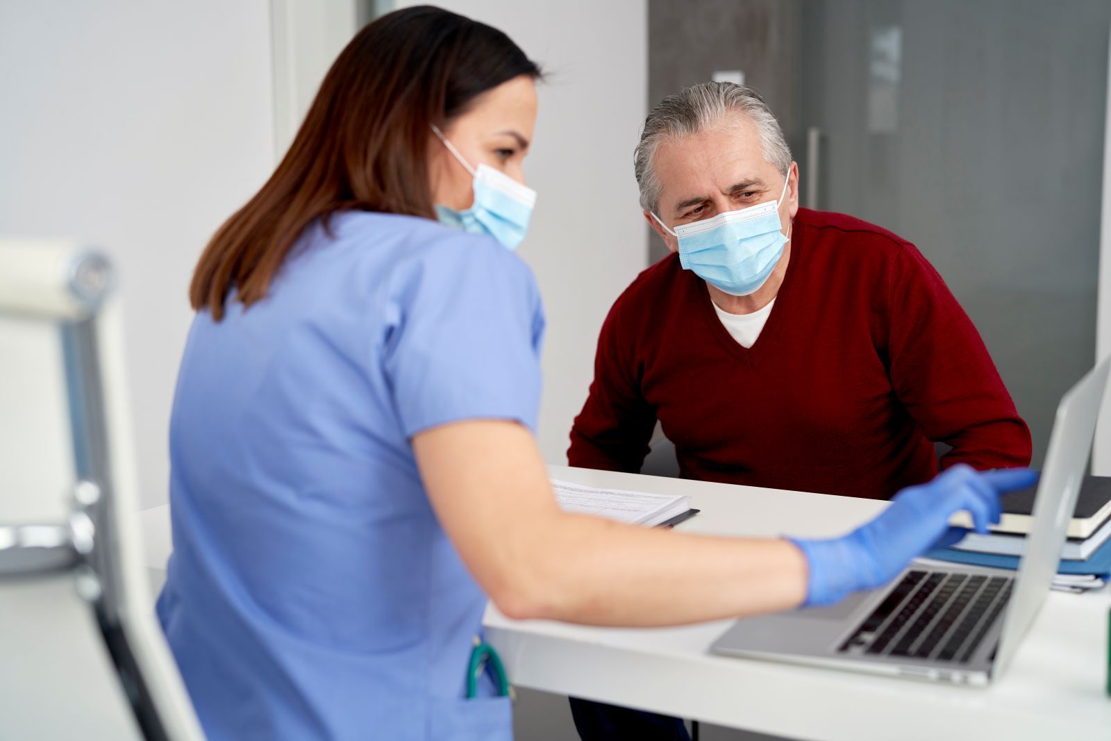 Nurse in blue scrubs is helping a patient with his Mohs questions