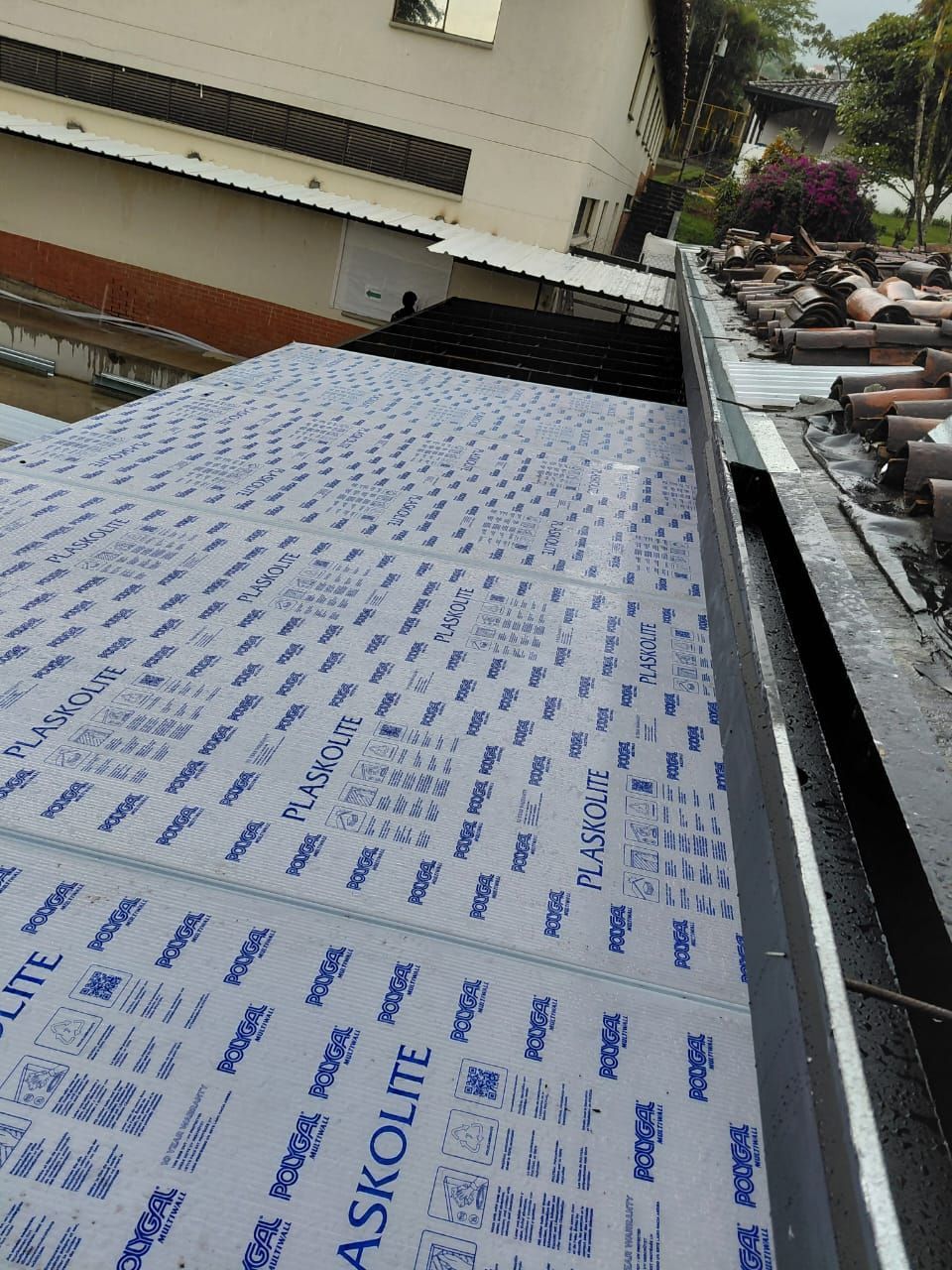 Lámina de techo ASKON blanca sobre un tejado inclinado junto a un edificio y una barandilla de terraza.