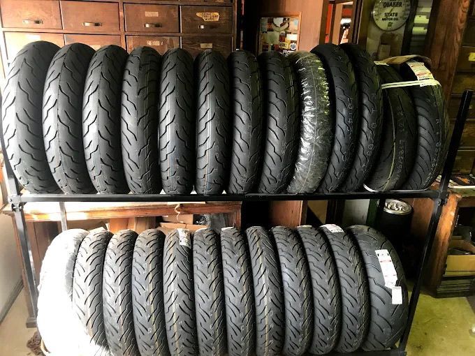 Black motorcycle tires stacked on shelves in a shop.