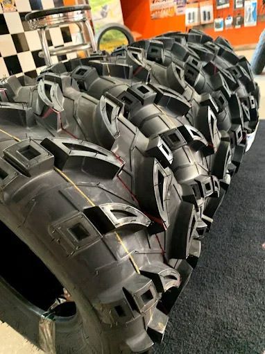 Close-up of several large black motorcycle tires with deep tread, on display in a shop.