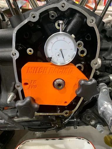 Dial indicator on orange engine cover inside a motorcycle engine case
