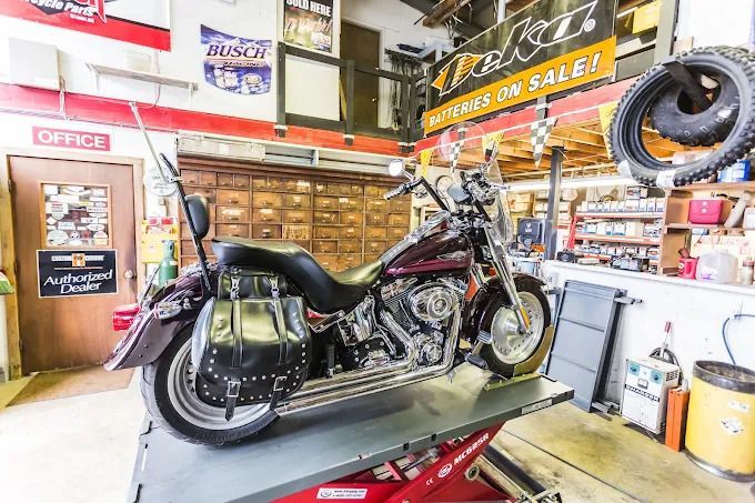 Motorcycle on display in a bright motorcycle shop with tools, parts, and sale signs