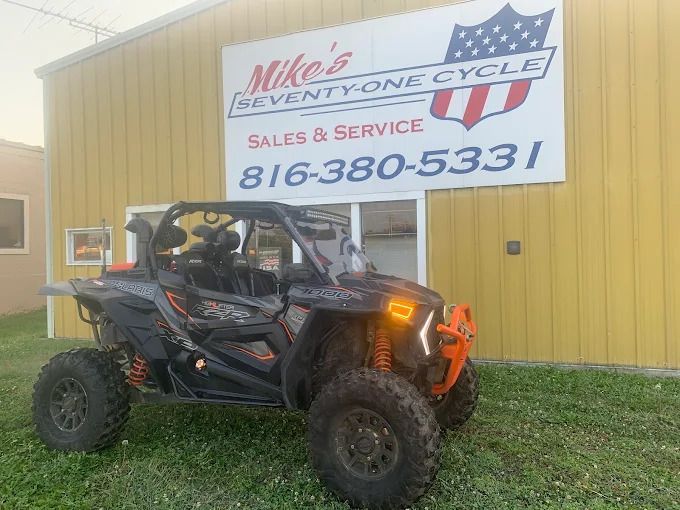 Black off-road UTV parked on grass outside Mike’s Event Pros Cycle sales and service shop sign