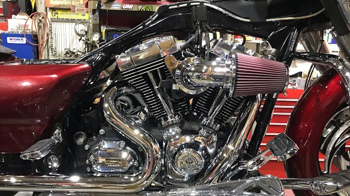 Shiny chrome custom motorcycle with a red seat and red air filter in a garage