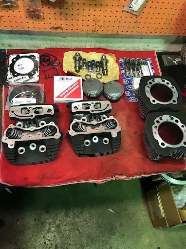 Assorted automotive parts and gaskets arranged on a red cloth-covered workbench in a shop.