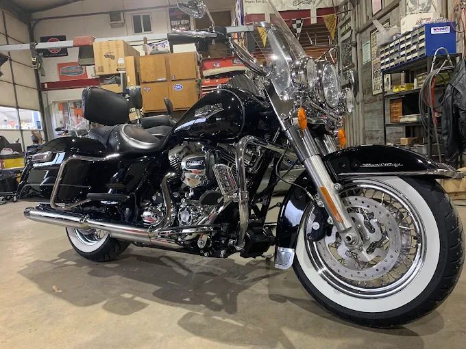 Black touring motorcycle with chrome details and whitewall tires in a garage workshop