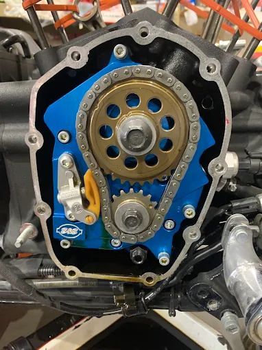 Close-up of a motorcycle engine timing gear assembly with blue and silver parts.