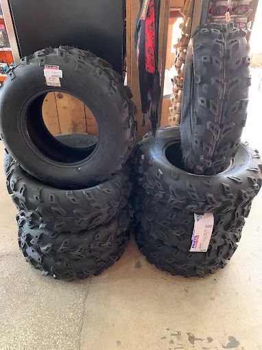 Stacked black off-road tires displayed on a store floor, with one tire standing upright on top.