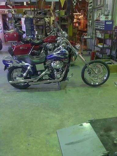 Custom chopper motorcycle with chrome and blue paint displayed in a shop garage.