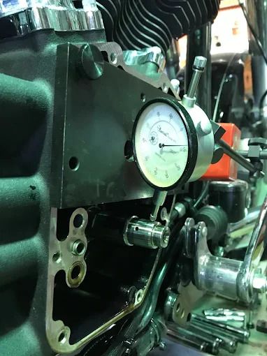 Close-up of a motorcycle engine with a pressure gauge attached during maintenance