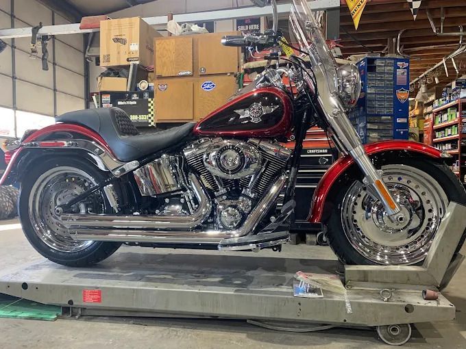 Black-and-red Harley-Davidson motorcycle on a trailer in a garage, side view.