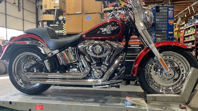 Black-and-red Harley-Davidson cruiser motorcycle parked indoors on a lift, side view