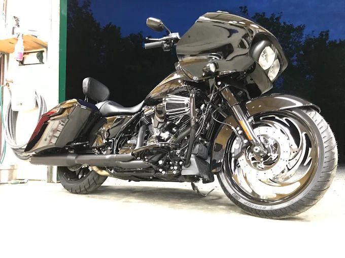 Black custom touring motorcycle parked indoors, side view with chrome wheels and dark bodywork