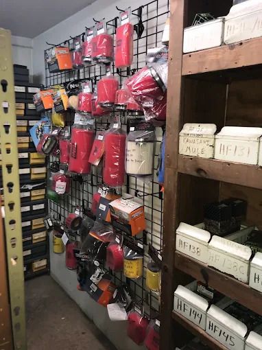 Store aisle with hanging camping gear and shelves of bins, mostly red and orange items.