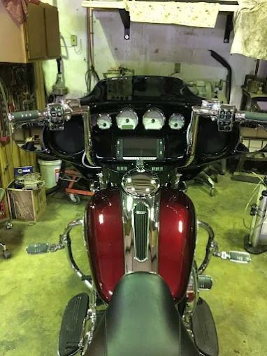 Front view of a burgundy touring motorcycle with chrome details in a garage, facing an open bay area