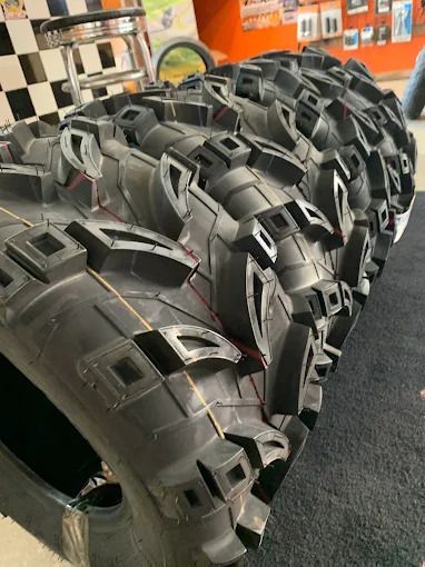 Rows of black treaded tires or tracks displayed indoors on a showroom floor.