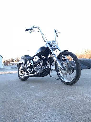 Chrome cruiser motorcycle parked on pavement at dusk, angled low against a pale sky