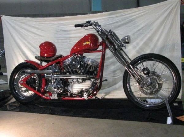 Red custom chopper motorcycle on display against a white backdrop