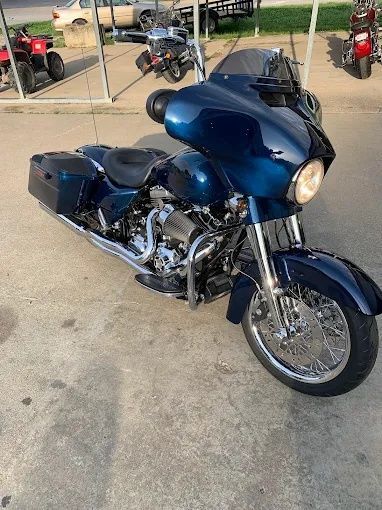 Blue touring motorcycle parked on a concrete lot with other bikes in the background