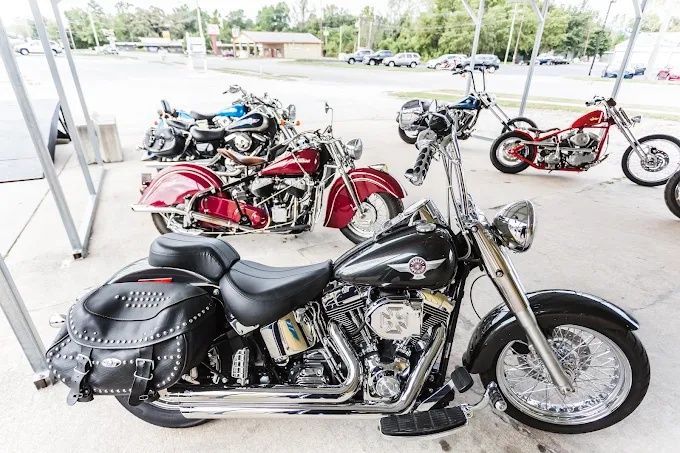 Black Harley-Davidson motorcycle in front with several parked motorcycles under a covered area.
