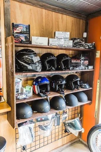 Shelves of motorcycle helmets in a wooden storage cabinet, with gloves and gear below.