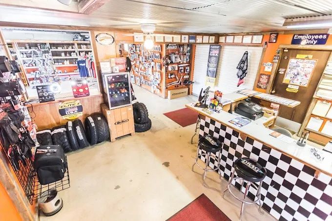 Small shop interior with checkered counter, shelves, posters, and several black bags on the floor.
