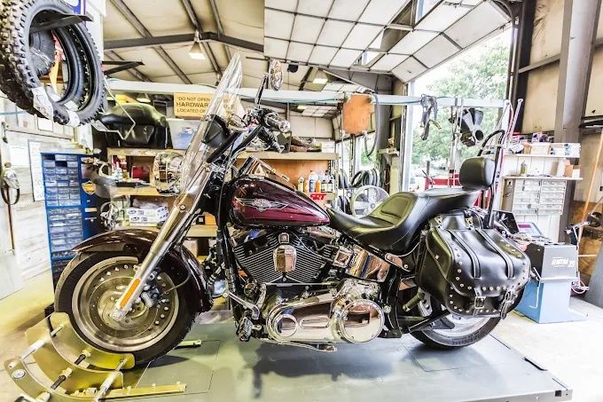 Custom black and chrome motorcycle in a workshop garage with tools and parts around it