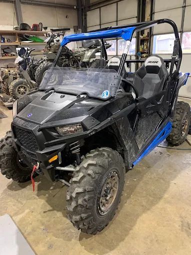 Black and blue off-road utility vehicle in a workshop garage, front view.