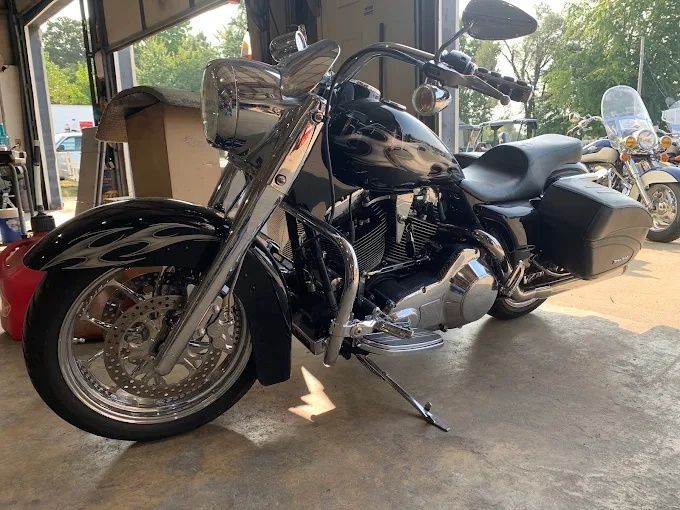 Black touring motorcycle parked indoors near a garage door, with chrome details and saddlebags.
