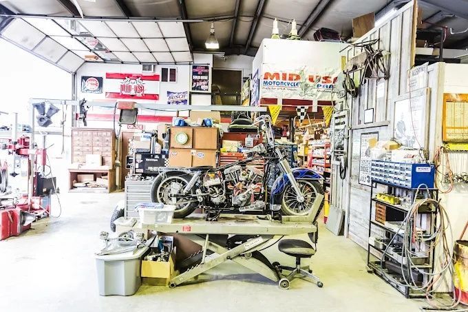 Motorcycle repair shop interior with bikes, tools, and parts in a cluttered workspace