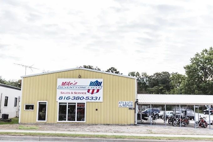 Yellow auto repair shop with sign and covered motorcycle parking beside it