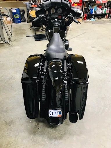 Rear view of a black touring motorcycle with large saddlebags in a garage