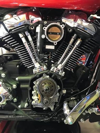 Close-up of a black V-twin motorcycle engine with chrome details and red bodywork above.