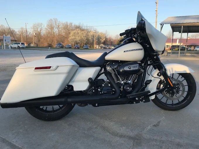 Cream and black touring motorcycle parked on pavement, side view with windshield and saddlebags.