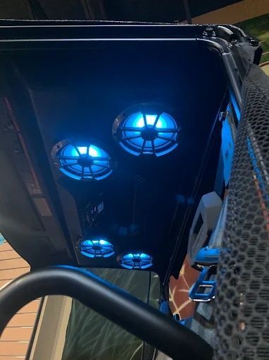 Blue-lit fans inside a computer case, seen through a side panel with mesh vents.