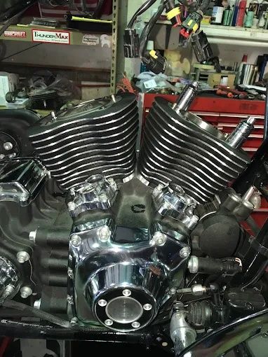 Chrome V-twin motorcycle engine in a garage, with black finned cylinders and polished metal parts