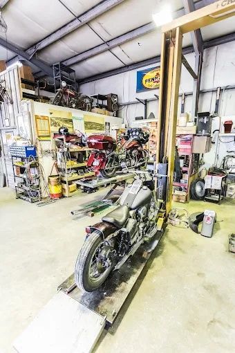Motorcycle on a lift inside a workshop, with tools and equipment in the background