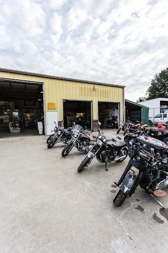 Motorcycles parked outside a yellow shop under a cloudy sky